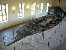 Une longue rangée de bateaux vikings, mettant en valeur le patrimoine du bateau moyen lenne dans ’The Longships’.