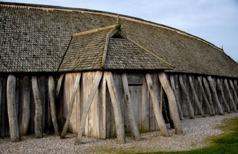 Maison viking en bois avec toit de chaume à l’extérieur d’une forteresse.